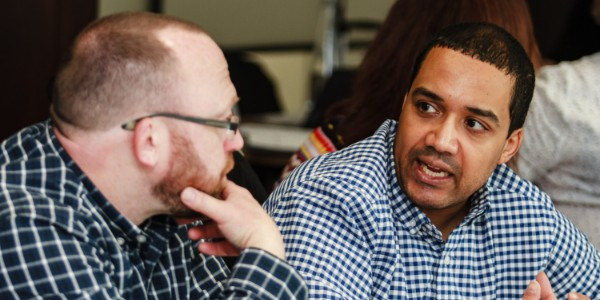 Image of 2 male member sat a table at one of our in-person events, in discussion